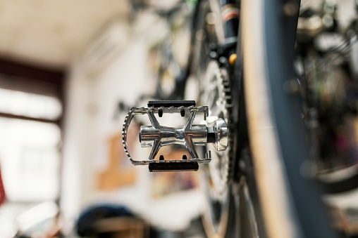 Bike service, pedal maintenance. Photo of Bike close up on gear wheel, pedal and wheel  in the sunny garage or workshop.