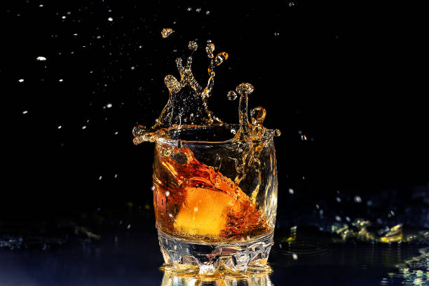 istock Whiskey glass with motion splashes from the ice. 942715930