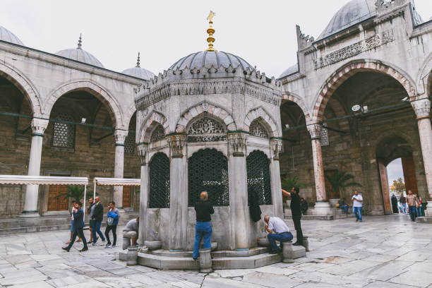 männer trinken heiliges wasser aus wasserhähnen in der nähe von süleymaniye-moschee - istanbul people faucet turkey stock-fotos und bilder