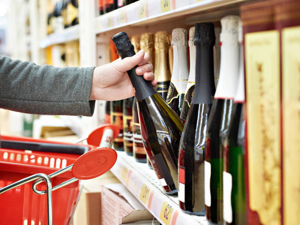 Bottle of champagne in hand at store Bottle of champagne in the hands of the buyer in the store alcohol shop stock pictures, royalty-free photos & images