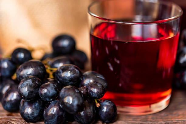 istock Red grape juice in glass and grapes close 942747676