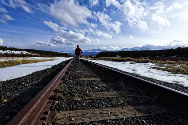 istock Man Walking ALong Train Tracks Mountain View 942747924