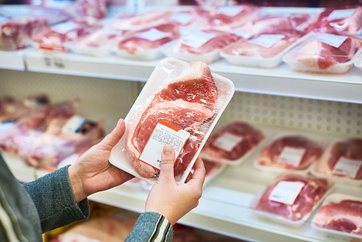 Buyer hands with pork meat packages at the grocery store
