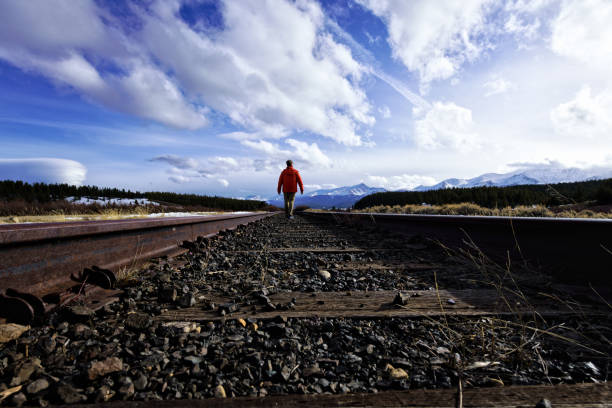 istock Man Walking ALong Train Tracks Mountain View 942751734