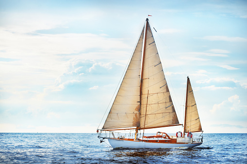 Vintage wooden two mast yacht sailing in a open sea on a clear day
