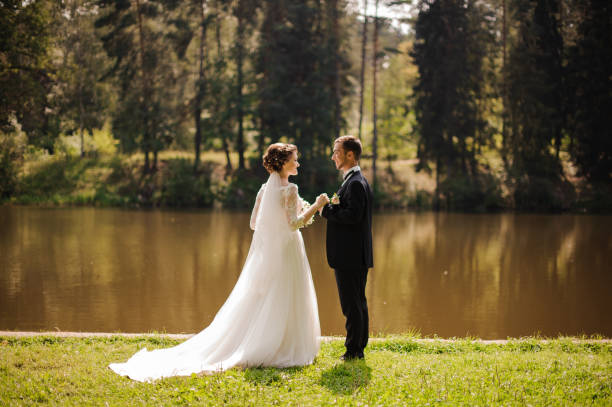 istock Young and beautiful bride with bridegroom on the river bank 942755588