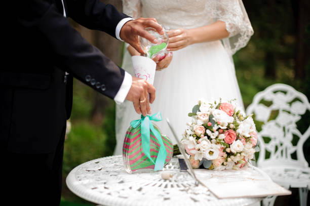 istock Bridegroom with bride pouring multi-colored sand against the green background 942756732