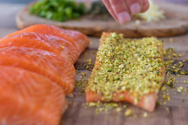 istock Hand sprinkling ground pistachio on raw salmon 942759698