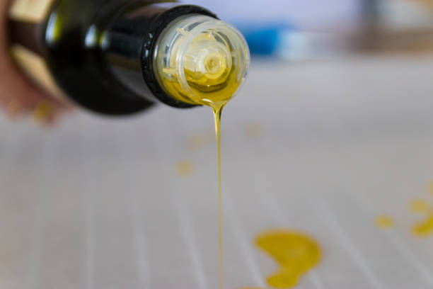 Olive oil pouring from the bottle on baking paper stock photo
