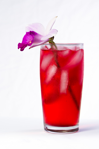 red cocktail garnished with a bamboo orchid  isolated on a white background