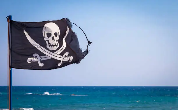 A damaged pirate flag during a strong windy day, with copyspace