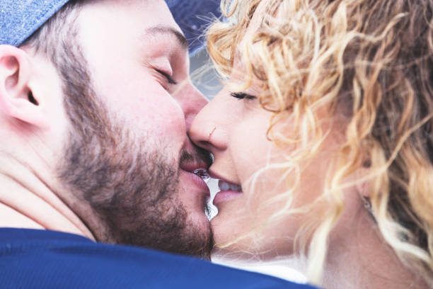 Reaching in for a kiss Close up of a happy couple kissing passionately on the farm while in an embrace. kissing on the mouth stock pictures, royalty-free photos & images