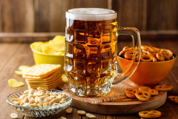 tazza di birra e snack su sfondo legno - beer nuts foto e immagini stock