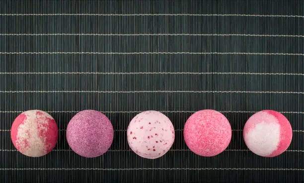 Colorful bath bombs arranged in a row on a bamboo placemat