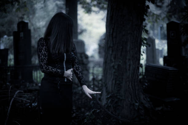 A solitary goth girl standing in an overgrown cemetery
