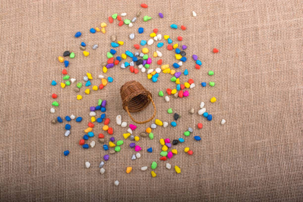 istock Basket and spilled colorful pebbles  on canvas background 942792072