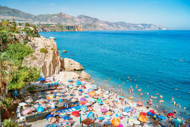 Beach in Nerja Costa del Sol Andalusia Spain Stock photograph of beach with crowd of people and the Mediterranean Sea in Nerja, Costa del Sol, Andalusia, Spain on a sunny day. nerja stock pictures, royalty-free photos & images