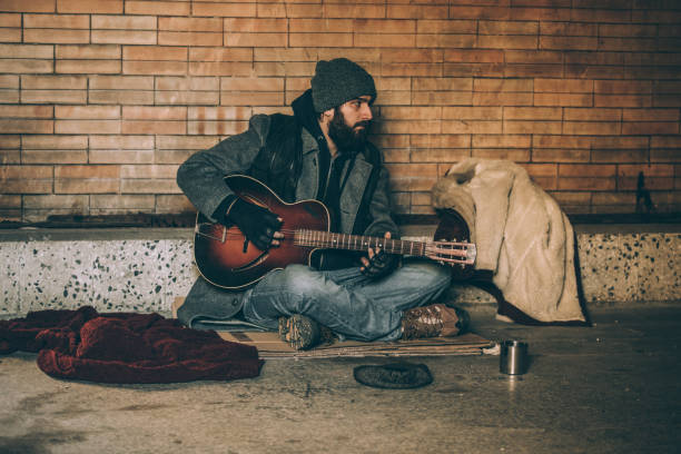 istock Young homeless man playing guitar 942813364