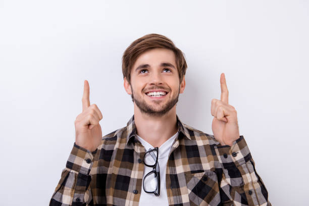 istock Handsome young smiling man in checkered shirt showing up on copyspace. 942815790