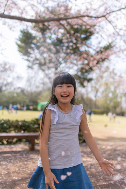 istock Little girl playing with fallen cherry petals 942816174