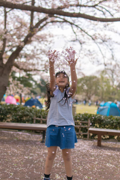 Little girl throwing cherry petals