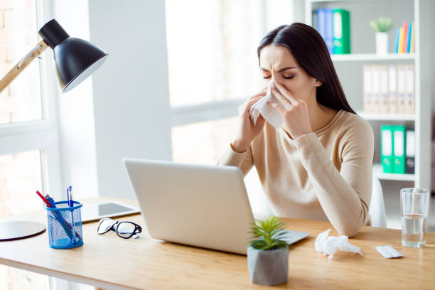 istock Ill woman sitting at the table with computer at work and using napkin 942818562