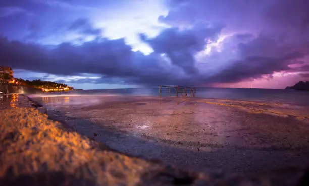 Storms on the sea with dark clouds, lightning and a view of the docks, long exposures