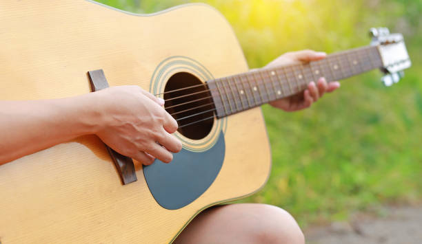 istock Female hand playing on acoustic guitar. Close-up. 942829524