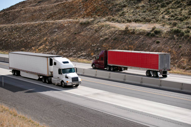 Two big rig semi trucks with trailers running on the highway in the opposite direction
