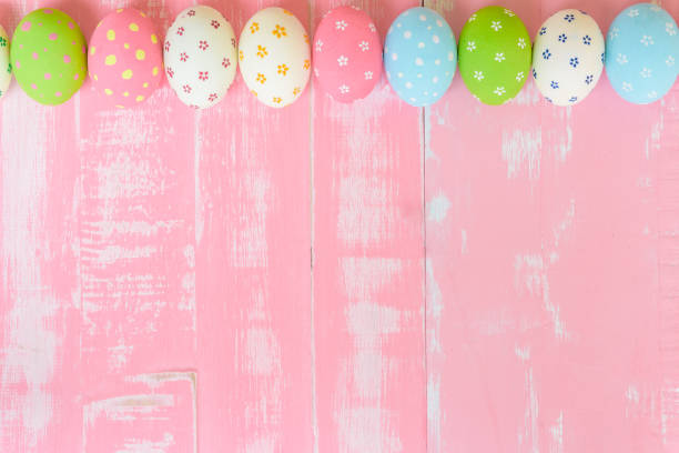 istock Happy easter! Row Easter eggs with colorful paper flowers on bright pink wooden background. 942843830