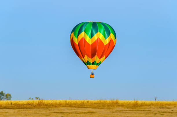istock multi-colored balloon with a basket, a flame of fire takes off into the blue sky 942846454
