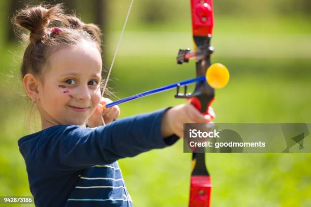 Archer De La Linda Chica Con El Arco En Día Soleado De Verano Niña Dispara Arco En El Parque Al Aire Libre Actividades Deportivas Con Los Niños Concepto De Deporte Y Estilo De Vida Con El Objetivo De Alta Foto de stock y más banco de imágenes de Tiro con arco