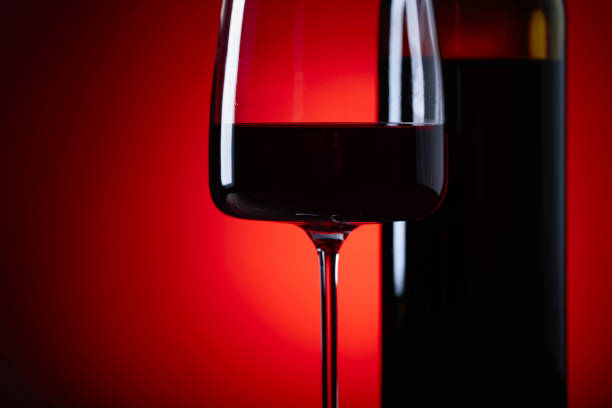 istock Glasses and bottle of rede wine on a red background. 942880804