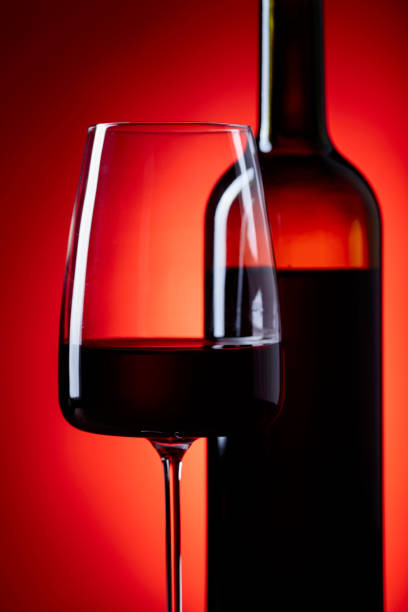 istock Glasses and bottle of rede wine on a red background. 942880810
