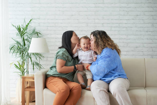 Motherhood Mothers kissing their happy laughing child on both cheecks lesbian stock pictures, royalty-free photos & images