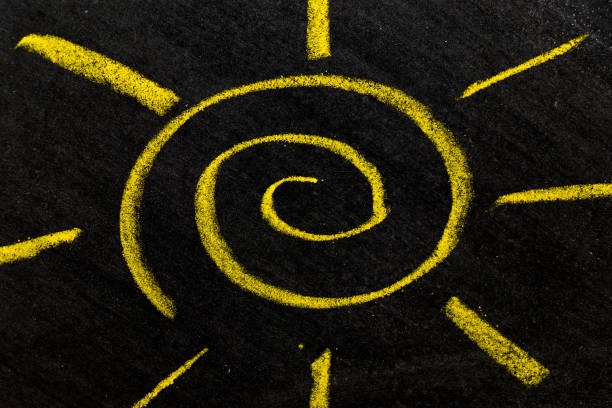 Yellow color chalk hand drawing as sun with light ray shape on black board background