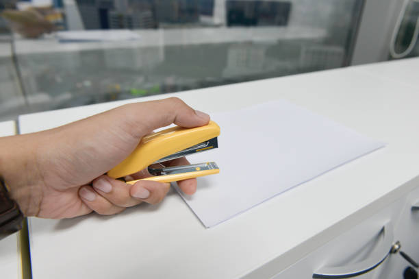istock Human hand is stapling the paper with yellow stapler 942885364