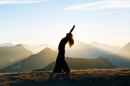 Woman dances at sunrise in the mountains