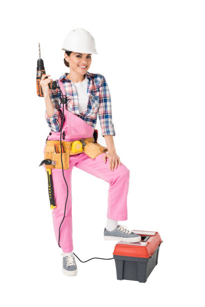 Female construction worker in uniform holding toolbox and drill isolated on white Female construction worker in uniform holding toolbox and drill isolated on white woman wearing tool belt stock pictures, royalty-free photos & images