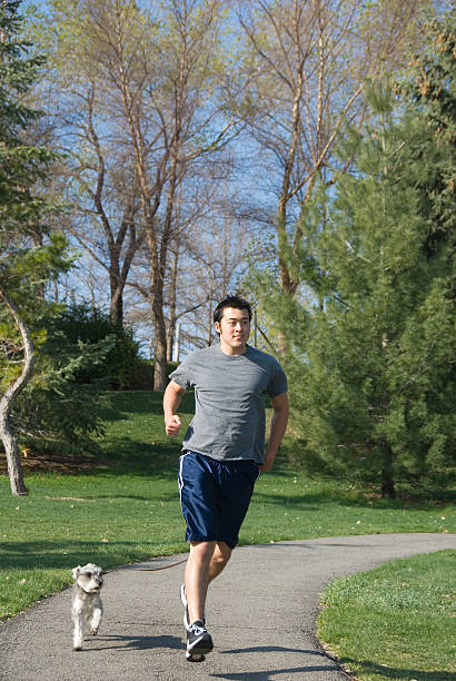 istock Fitness: asian man running in the park with his dog 94289799