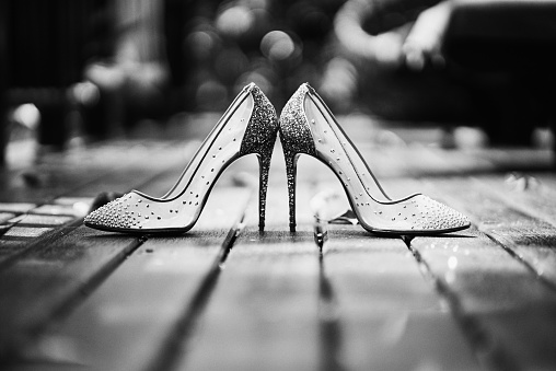 The Black and White of women glittering high heels shoes on the wooden floor with bokeh on background