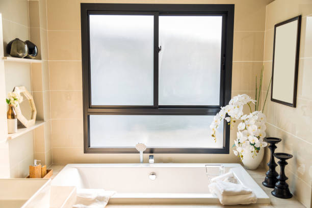 istock A luxury beige bathroom with a white bathtub and white towel with a white artificial flowers in a ceramic pot 942905596