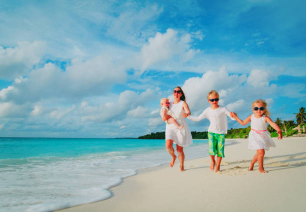 istock mother with kids play run on tropical beach 942905896