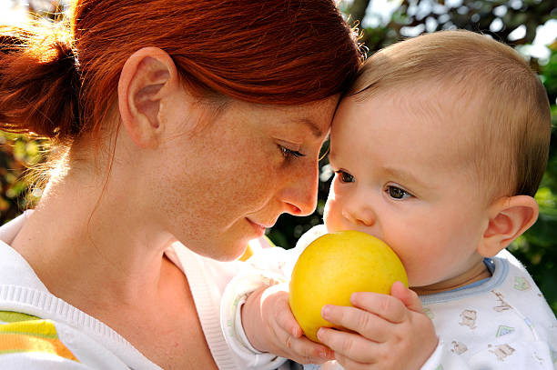 Caucasian mother and her Asian daughter in the orchard in summer