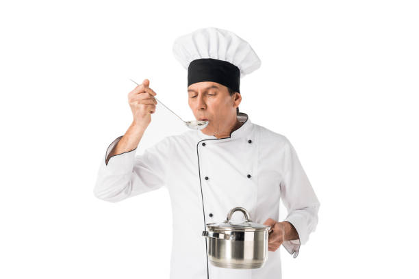 istock Man in chef uniform holding pan and tasting food isolated on white 942908996
