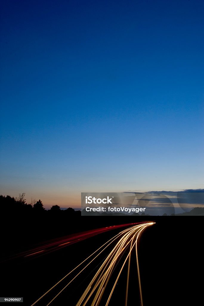 Car lights streaking into deep blue sky  Lighting Equipment Stock Photo