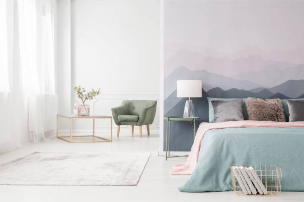 Golden frame table and armchair Modern golden frame coffee table with an elegant glass vase and a comfortable green armchair in a white studio interior with a large bed bed decoration stock pictures, royalty-free photos & images