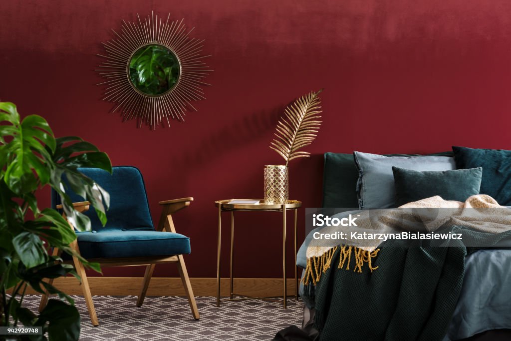 Sophisticated red bedroom with mirror Gold table between green armchair and bed in sophisticated red bedroom interior with mirror Bedroom Stock Photo