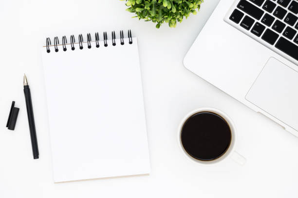 istock White office desk table with blank notebook page with pen, laptop and coffee. Top view with copy space, flat lay. 942926860