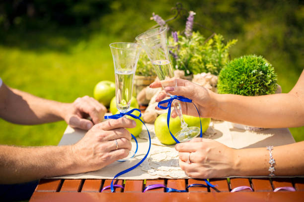 Hands with glasses of champagne in the park at a picnic